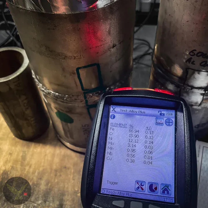 XRF analyzer screen showing an alloy grade result beside stainless steel pipe