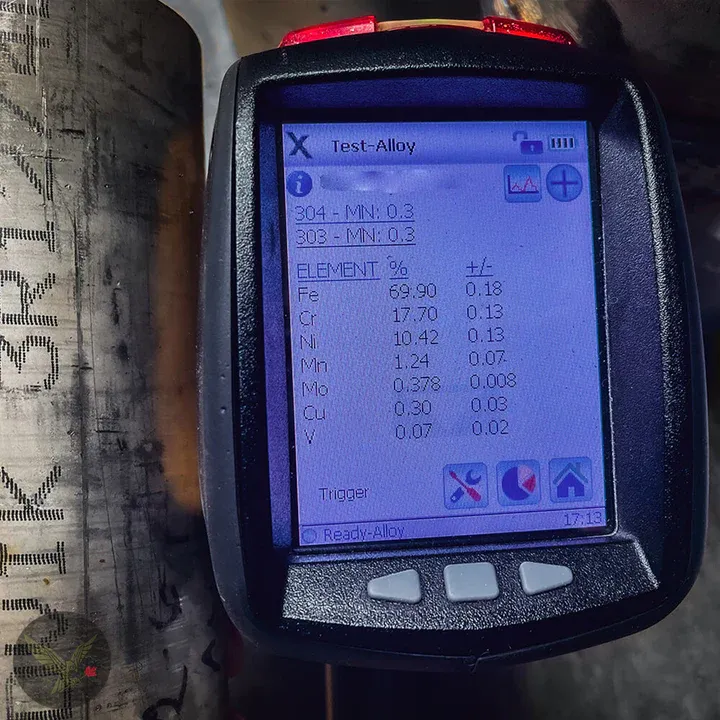 Portable XRF analyzer reading an alloy result against stamped pipe