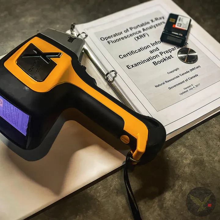 Handheld XRF analyzer resting on the operator certification study guide